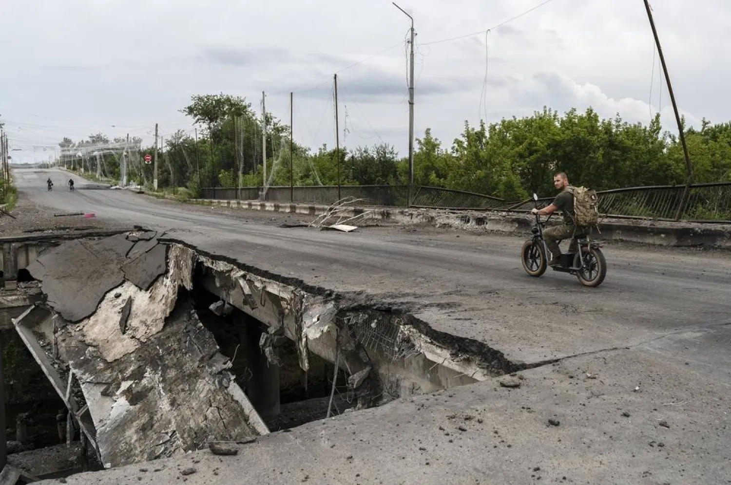 A handout photo made available by the press service of the 93rd Separate Mechanized Brigade of the Ukrainian Armed Forces on 26 July 2026 shows a man ride a scooter on a damaged bridge in Druzhkivka in the Donetsk region, Ukraine, 25 July 2026, amid the ongoing Russian invasion. (EPA/93rd Separate Mechanized Brigade / Handout)