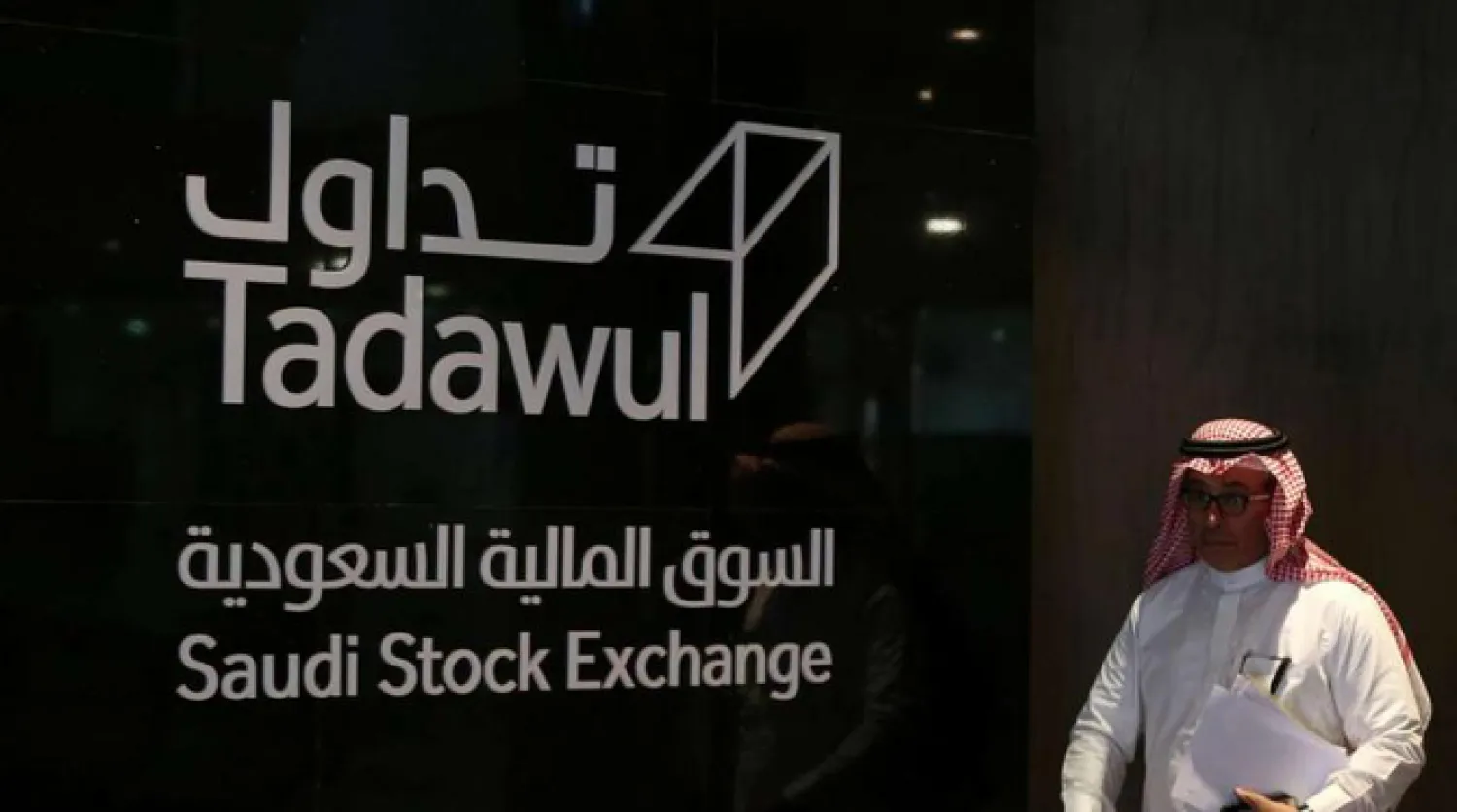 رجل يعبر أمام شعار «تداول» في السوق السعودية (أ.ف.ب)