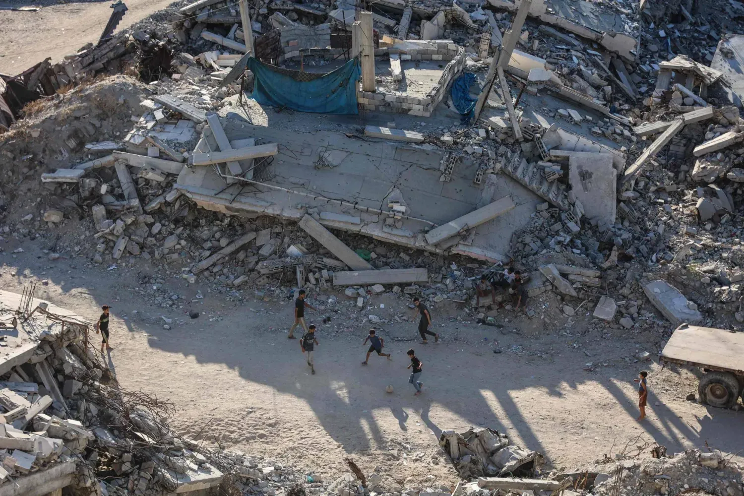Pazartesi günü Gazze şehrinde yıkılmış binaların arasında top oynayan çocuklar (AFP)