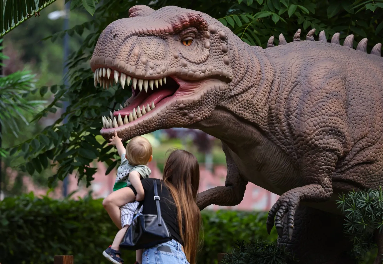 A woman and her child examine a life-size dinosaur figure during sunny weather in Moscow, Russia, 22 July 2026. EPA/SERGEI ILNITSKY