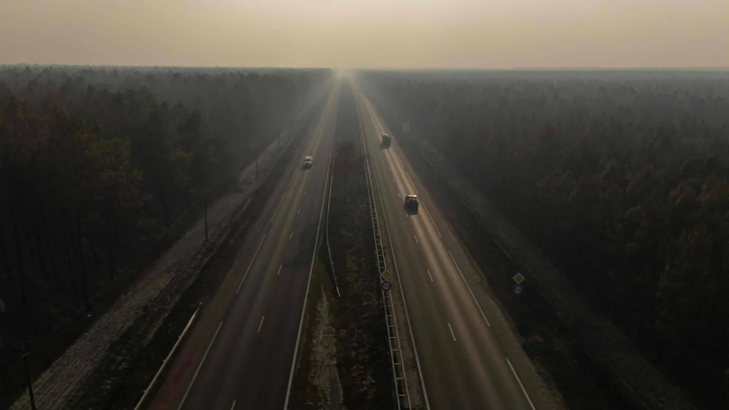 This aerial view shows vehicles making their way along a road leading to Le Temple between fire damaged forest following wildfires on July 28, 2026. (AFP)