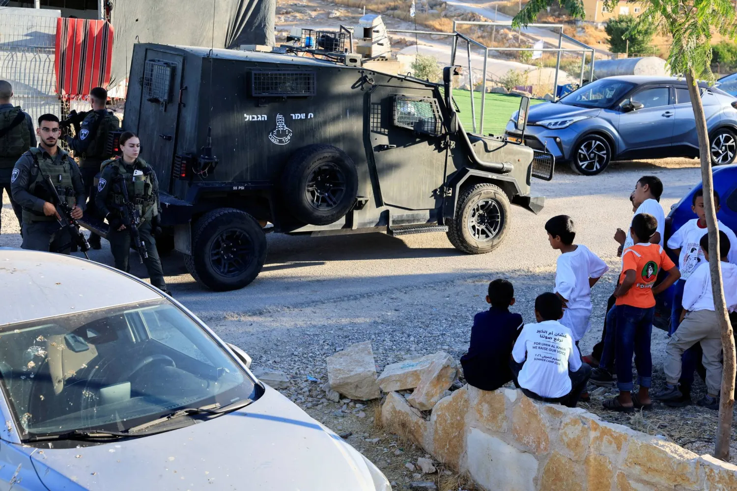 ينظر فتيان فلسطينيون إلى شرطة الحدود الإسرائيلية في أم الخير بالضفة الغربية المحتلة (رويترز)