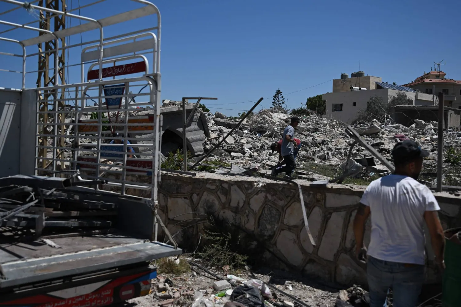 Workers collect scrap metal from the rubble of destroyed houses in Zawtar al-Gharbiyeh on July 28, 2026, as residents return to inspect their homes after the Lebanese army deployed to the southern village as part of a framework deal reached with Israel. (AFP)