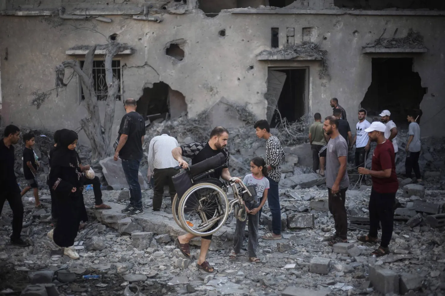 فلسطينيون يتفقدون يوم الأربعاء مباني تضررت ودُمرت جراء غارات إسرائيلية شُنّت الليلة السابقة في دير البلح بوسط غزة (أ.ف.ب)