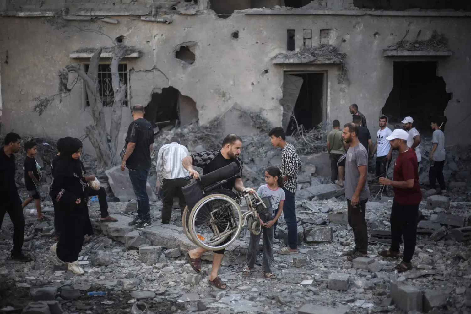Gazze Şeridi’nin orta kesimindeki Deyr el-Balah’ta bir önceki gece İsrail hava saldırıları sonucu hasar gören ve yıkılan binaları inceleyen Filistinliler (AFP)