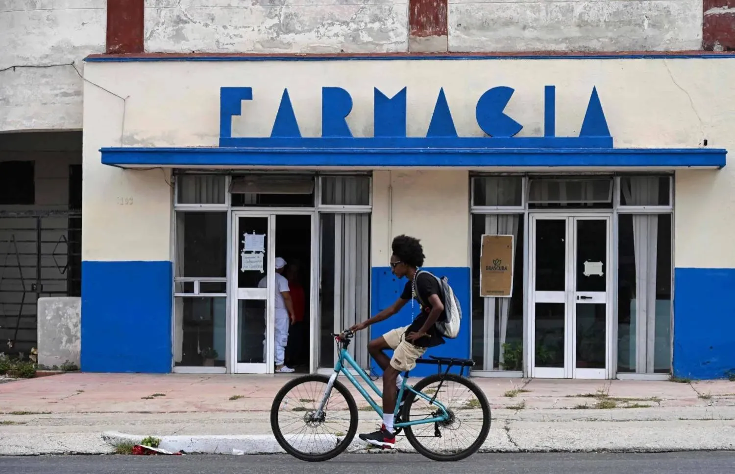 A man drives his bicycle past a pharmacy in Havana (AFP)