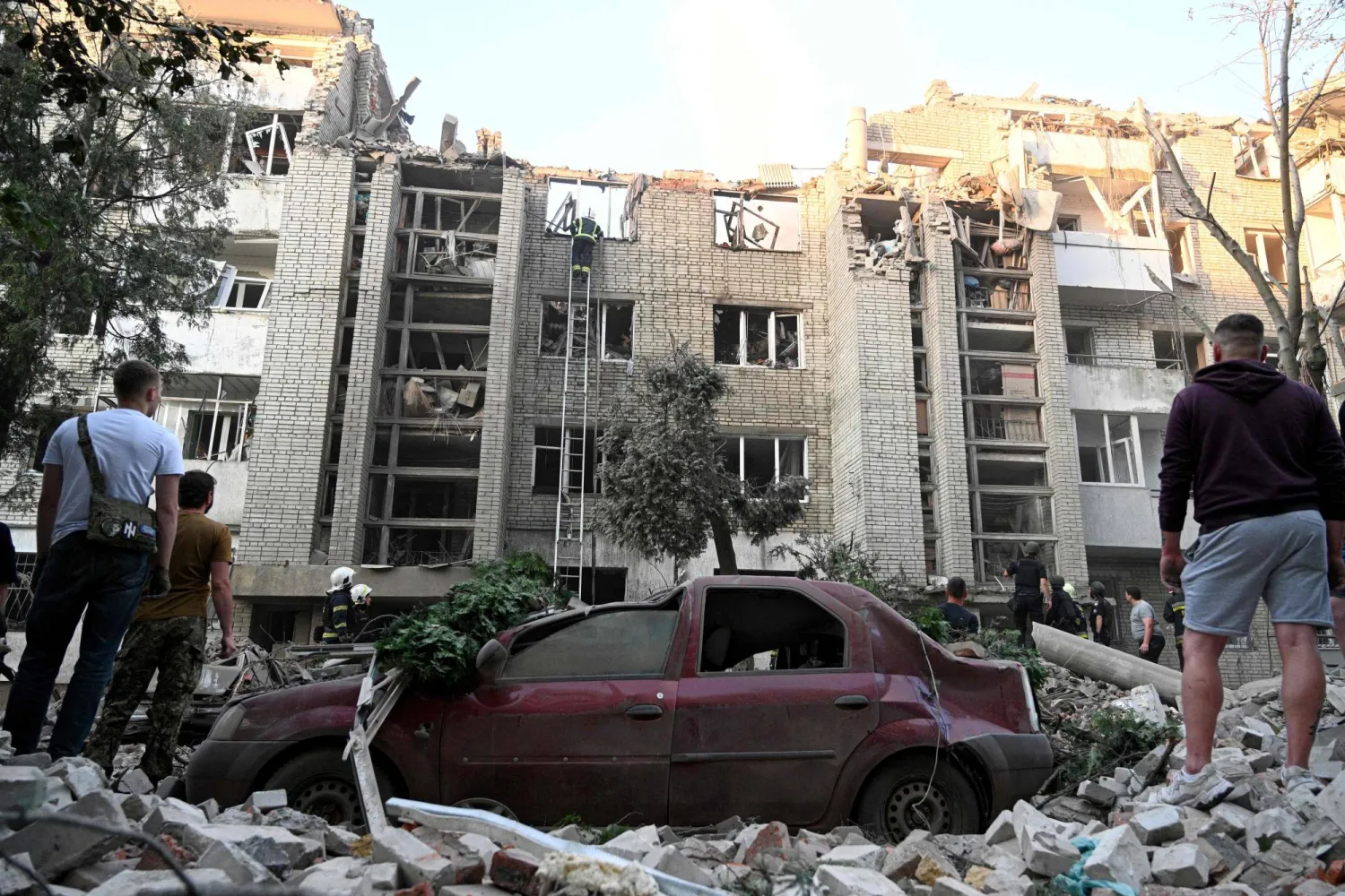 TOPSHOT - Local residents watch as first responders operate at a residential building partially destroyed as a result of Russian missile strikes in the western Ukrainian city of Lviv on July 30, 2026, amid the Russian invasion in Ukraine. (Photo by YURIY DYACHYSHYN / AFP)