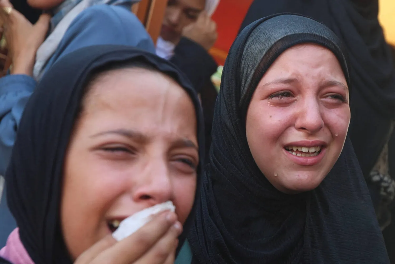 فتاتان تنتحبان خلال جنازة فلسطينيين قُتلوا في غارات إسرائيلية استهدفت خياماً في خان يونس جنوب غزة (رويترز)