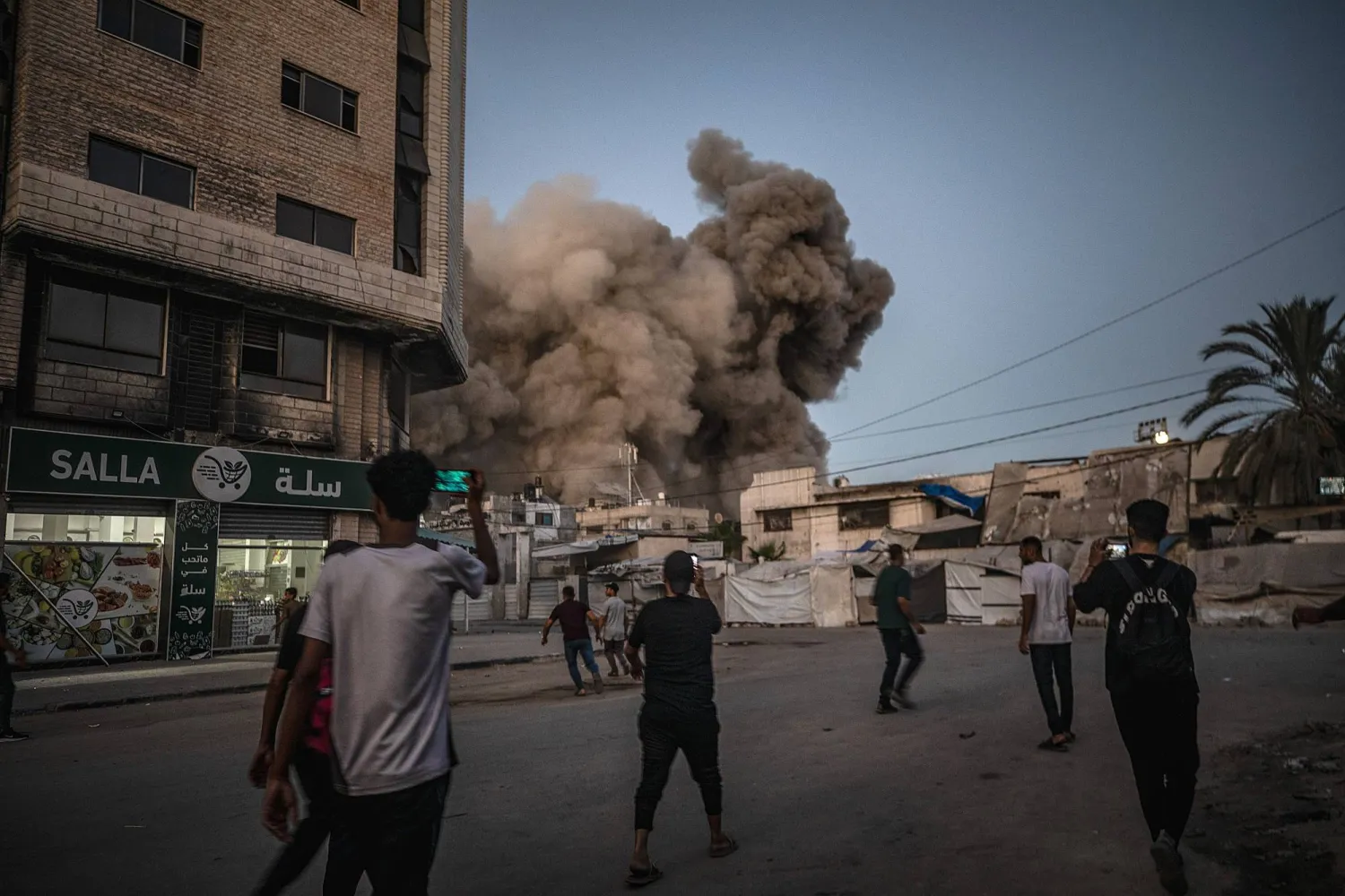 فلسطينيون يشاهدون قصفاً إسرائيلياً استهدف قطاع غزة (إ.ب.أ)