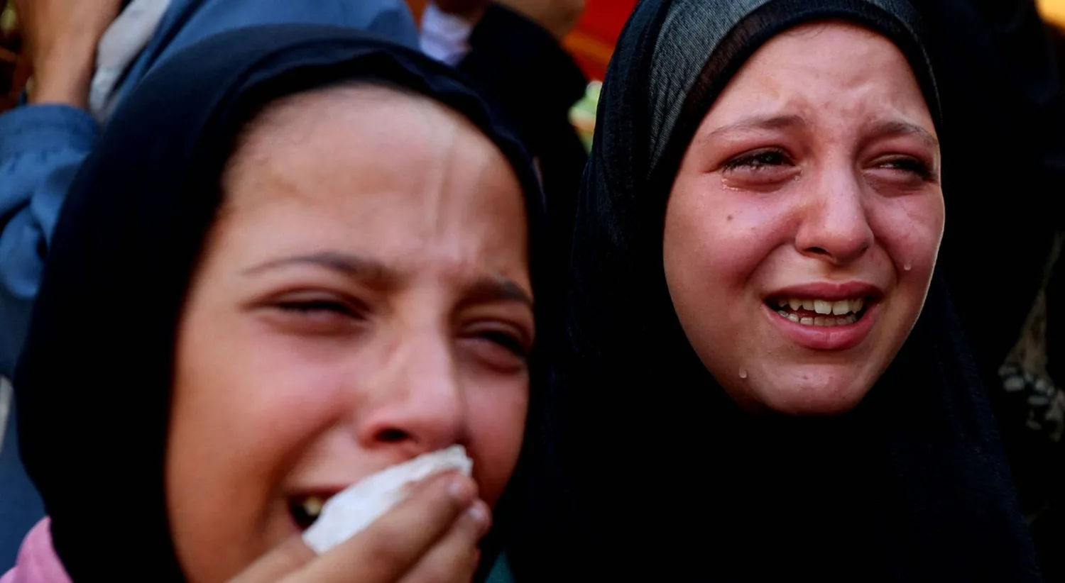  فتاتان تنتحبان أمس خلال جنازة فلسطينيين قُتلوا في غارات إسرائيلية استهدفت خياماً في خان يونس جنوب غزة (رويترز)