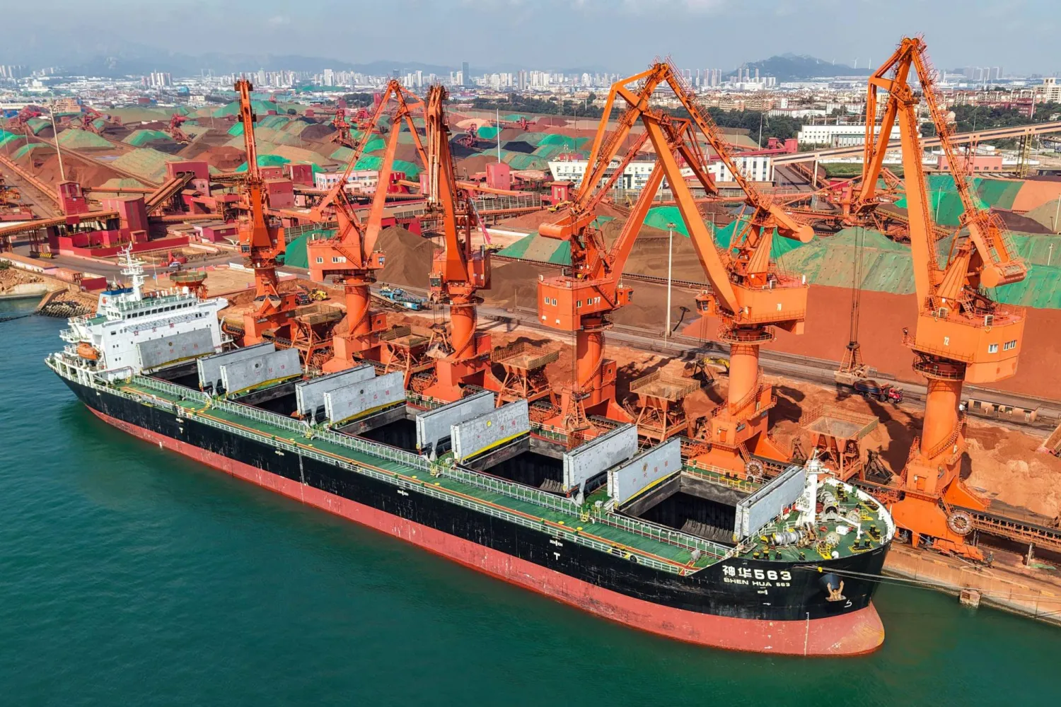 A cargo ship unloads imported iron ore at a port in Qingdao, in China's eastern Shandong province on July 30, 2026. (Photo by CN-STR / AFP)  