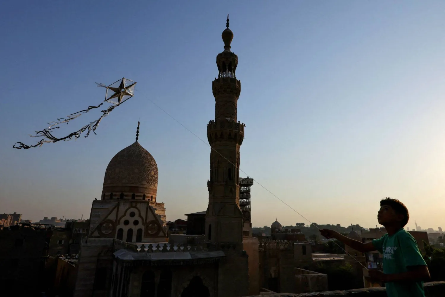 طفل يلهو بطائرة ورقية أمام مسجد السلطان قايتباي في وسط العاصمة المصرية القاهرة (رويترز)