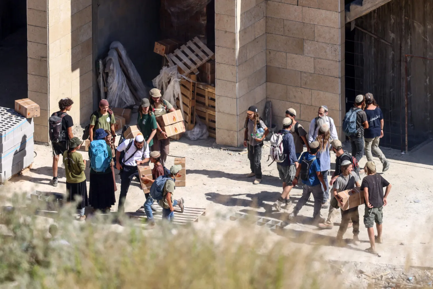 Israeli settlers, are seen illegally taking building materials from a Palestinian owned home under construction, as they take part in an organized march between the Palestinian villages of Sarra and Tell, southwest of the city of Nablus in the Israeli- occupied West Bank, in memory of two Israelis killed last week during clashes involving settlers entering the village of Tell on July 31, 2026. (Photo by Zain JAAFAR / AFP)
