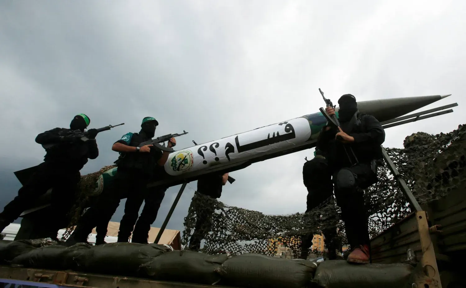 Hamas militanları, 14 Aralık 2014'te Gazze Şeridi'nde hareketin kuruluşunun 27. yıldönümü kutlamaları sırasında yerel yapım bir Kassam roketinin sergiliyor (Reuters)
