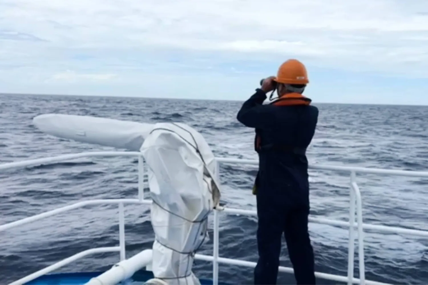 In this photo taken from video provided by the Philippine Coast Guard, a member of the Philippine Coast Guard (PCG) on board the BRP Malapascua (MRRV-4403) continues its search and rescue operations in the vicinity waters off a Chinese-occupied shoal in the South China Sea, Tuesday, July 28, 2026, following the reported sinking of Vietnamese cargo vessel Khoi Nguyen 18. (Philippine Coast Guard via AP)
