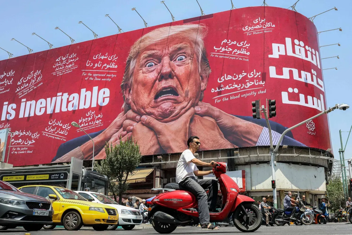 28 Temmuz 2026'da Tahran'da, ABD Başkanı Donald Trump'ın resminin yer aldığı ve üzerinde İngilizce ile Farsça olarak "İntikam kaçınılmazdır" yazan bir reklam panosunun önünden geçenler, (AFP)