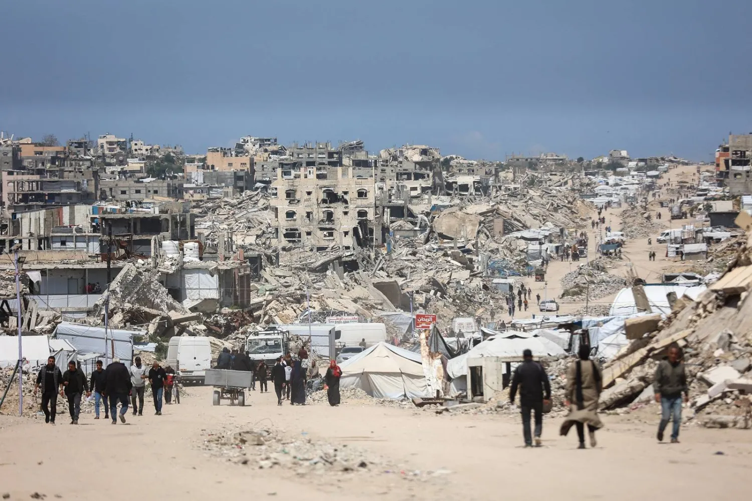 فلسطينيون يسيرون وسط أنقاض المباني المدمرة في مخيم جباليا للاجئين شمال قطاع غزة (أ.ف.ب)