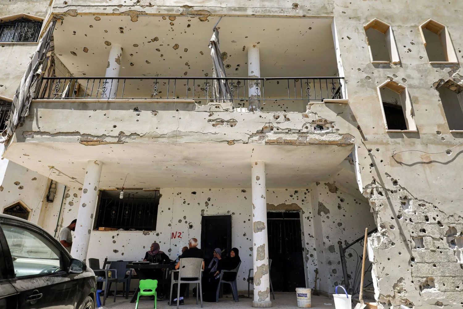 31 July 2026, Lebanon, Zawtar Al-Gharbieh: A Lebanese family sit in the shadow of their bullet riddled and shell-pocked building in the southern Lebanese village of Zawatar al-Gharbieh. Photo: Marwan Naamani/ZUMA Press Wire/dpa