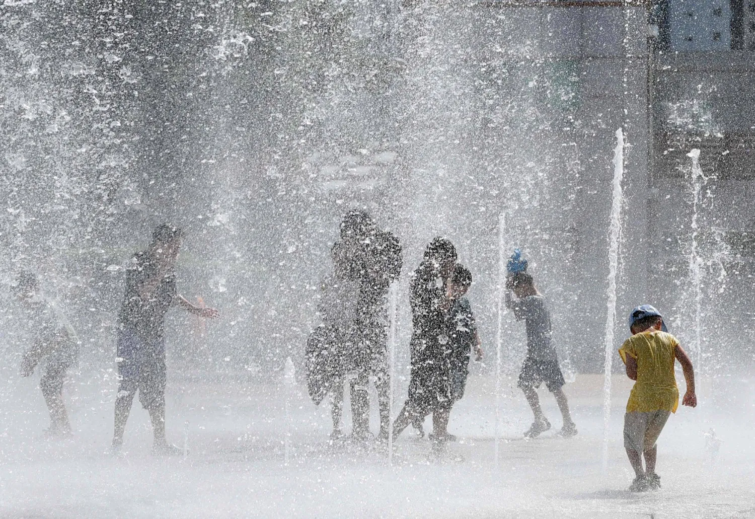 This picture taken on July 31, 2026 shows people playing in a fountain to cool off in Yangsan. (Yonhap/AFP)