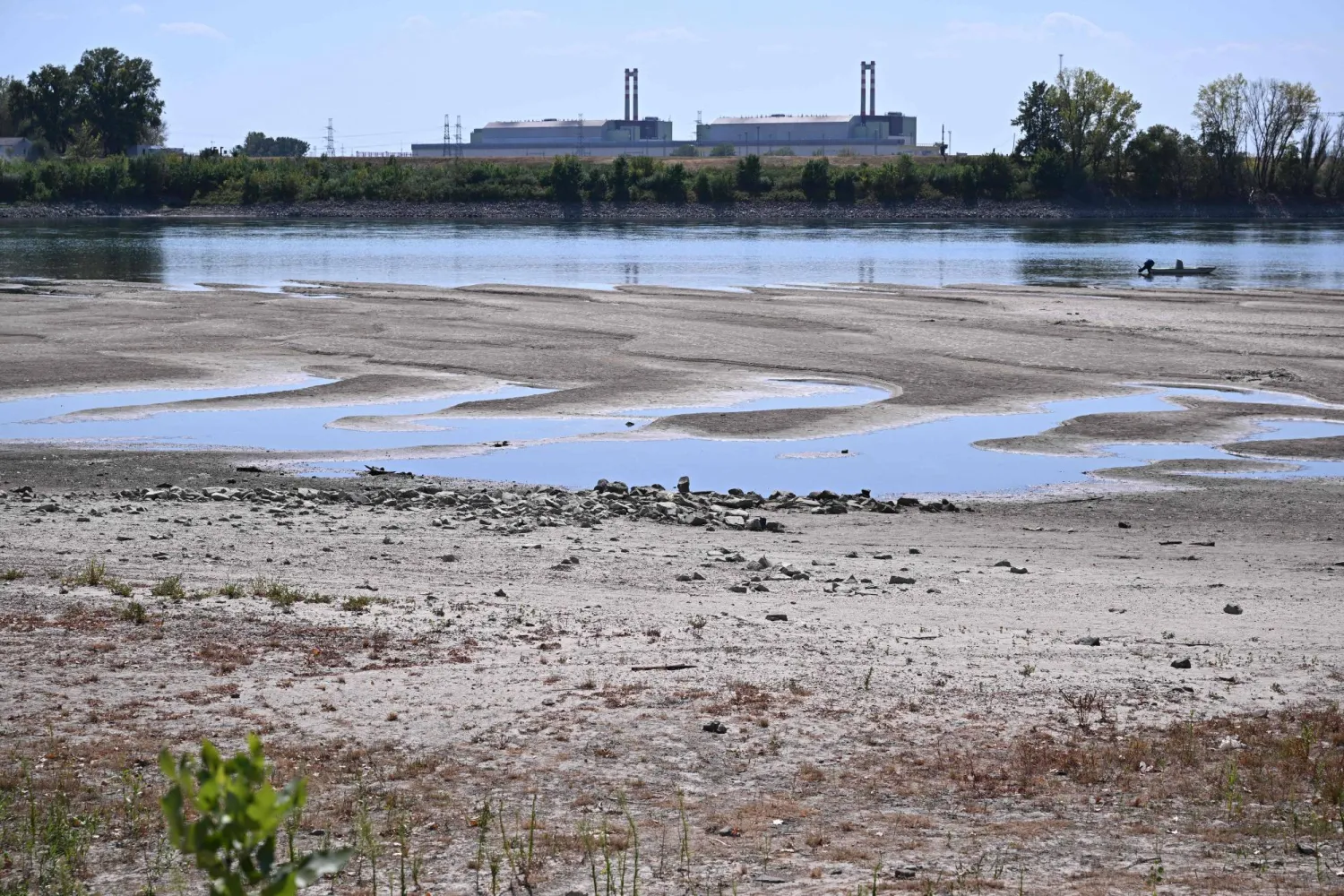 The dried-up Danube riverbed is pictured with the Paks power plant at the background, near Dunaszentbenedek, close to Paks town on July 31, 2026. (Photo by Attila KISBENEDEK / AFP)
