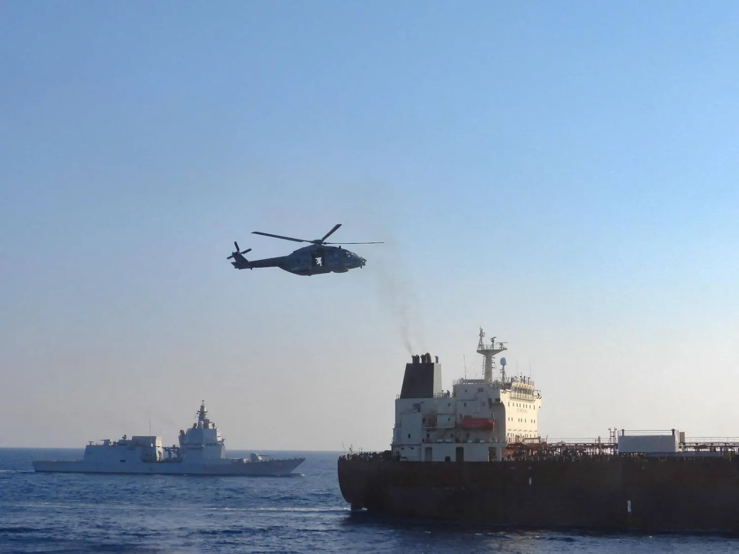 An Italian military helicopter flies above the oil tanker Toa Payoh, foreground, as the Italian Navy ship Thaon di Revel sails nearby during an inspection by the European Union’s EUNAVFOR MED Irini mission in international waters west of the Italian island of Pantelleria, August 2, 2026. (Italian Defense Ministry/Handout via Reuters) 