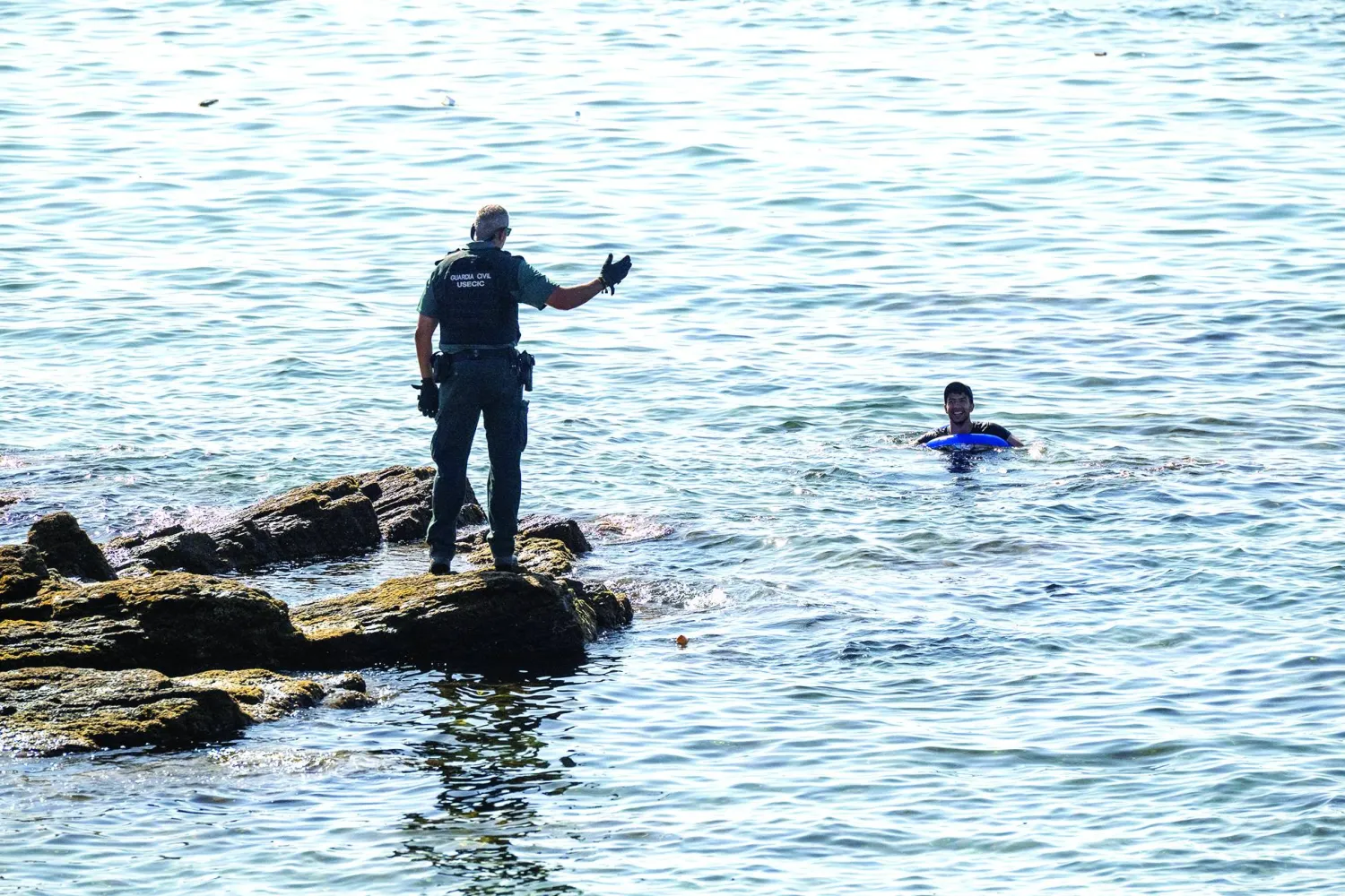 02 August 2026, Spain, Ceuta: A Spanish Civil Guard officer warns migrants attempting to cross into the Spanish enclave of Ceuta from Morocco. Photo: Marcos Moreno/EUROPA PRESS/dpa