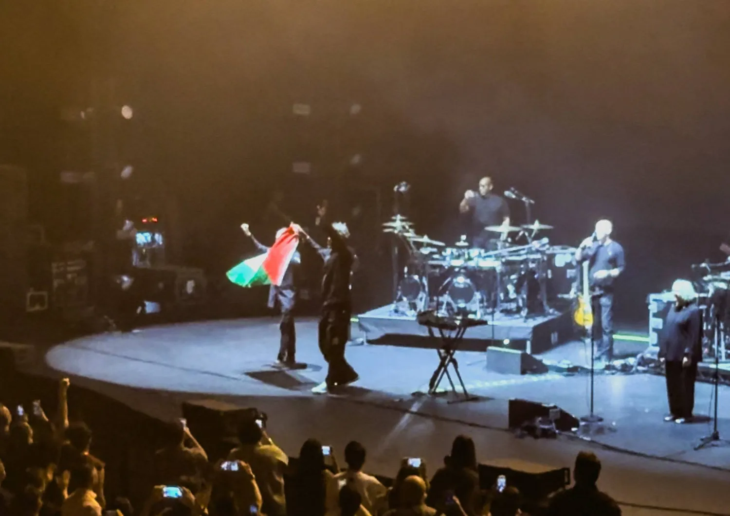 Robert Del Naja and Grant Marshall from Massive Attack stand with a Palestinian flag onstage at the end of their performance in Singapore, July 29, 2026, in this screengrab from video obtained from social media. (Simran Panaech/via Reuters)