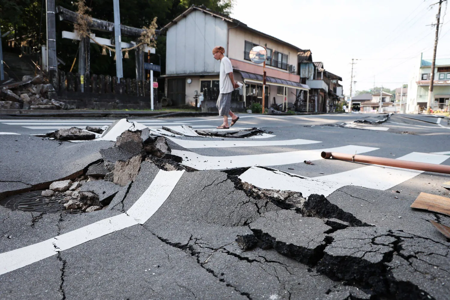  A man walks along a destroyed road in Uki, Kumamoto prefecture on August 3, 2026, following the July 28 earthquake. (Jiji Press/AFP)