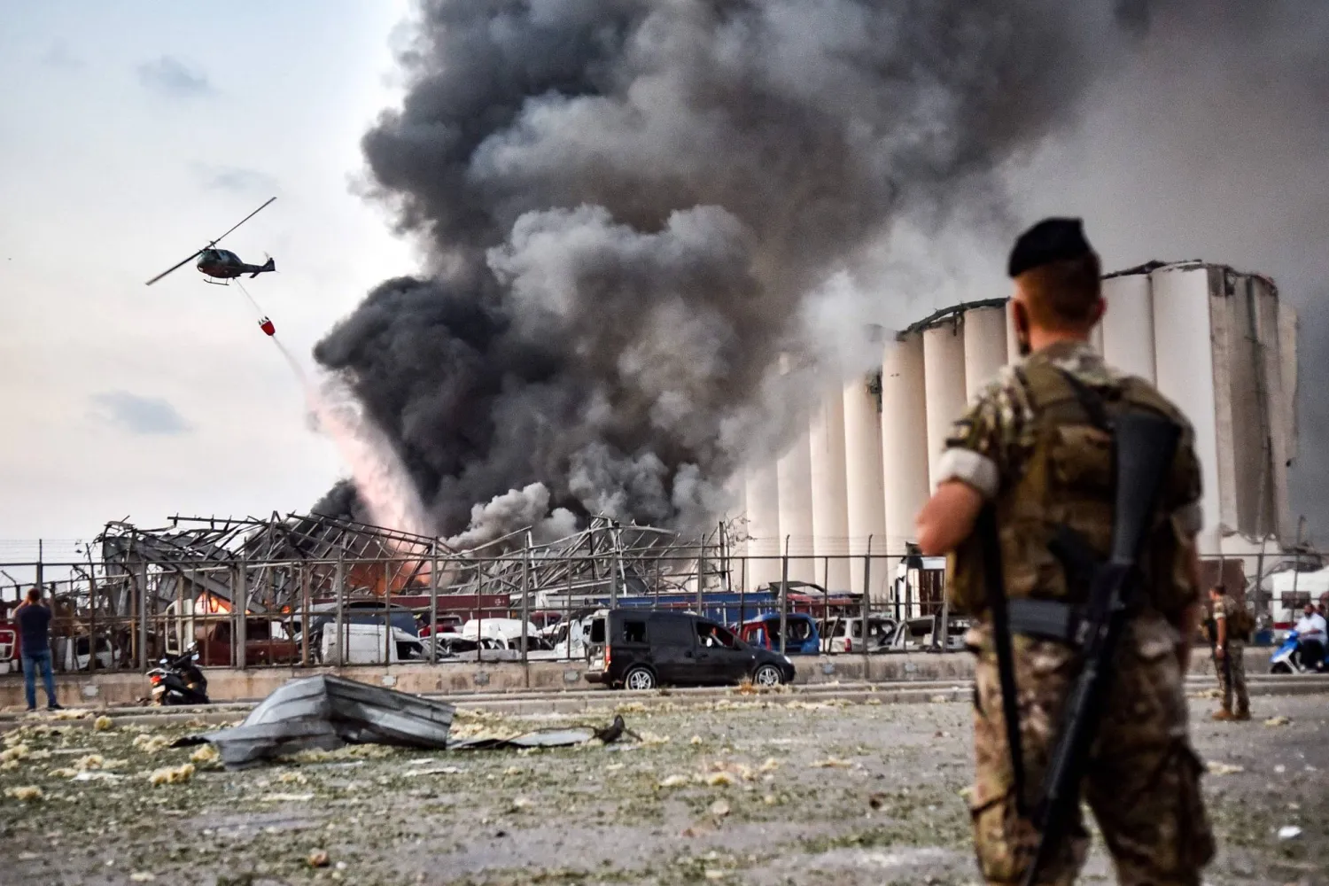 Lebanese army soldiers stand while behind a helicopter puts out a fire at the scene of an explosion at the port of Lebanon's capital Beirut on August 4, 2020. (AFP)