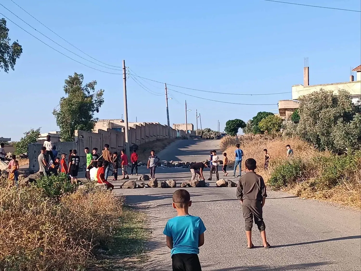 Suriye'nin güneyindeki Dera'nın batı kırsalında bulunan Yermuk Havzası'ndaki Abidin köyünde çocuklar, İsrail ordusuna ait devriyelerin köye girmesini engellemek amacıyla yolu kapatıyor. (Facebook)