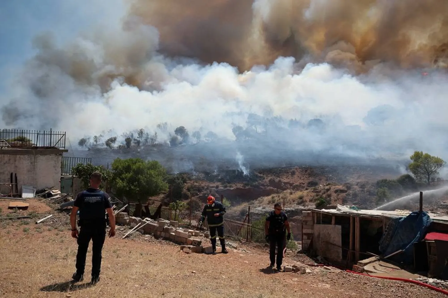  A firefighter and police officers work beside a burning area near Nea Peramos, as wildfires hit West Attica, Greece, August 3, 2026. (Reuters)