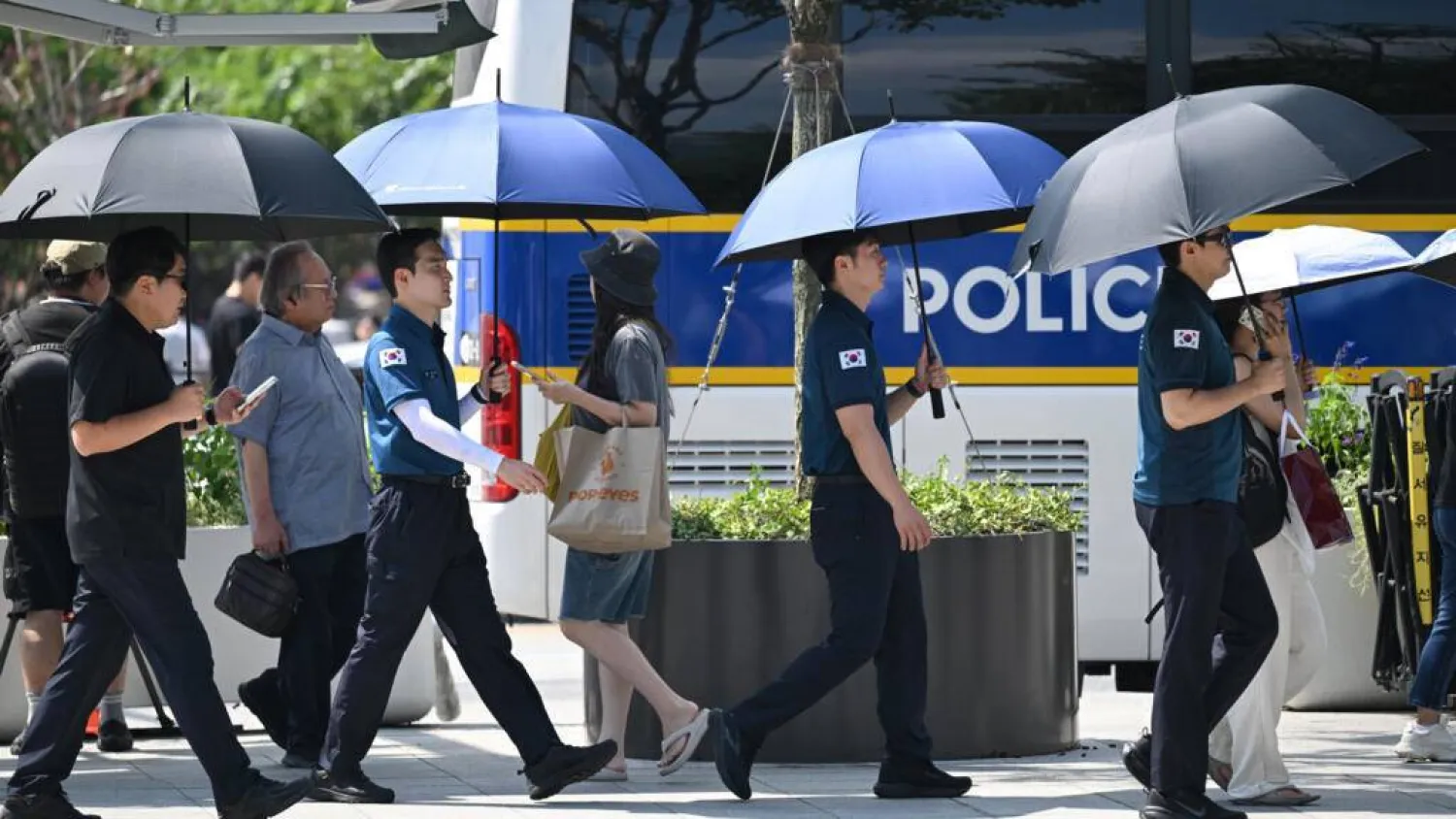 Police officers use umbrellas to shield from the sun on a street in Seoul as a scorching heat wave continues to grip South Korea. Jung Yeon-je / AFP
