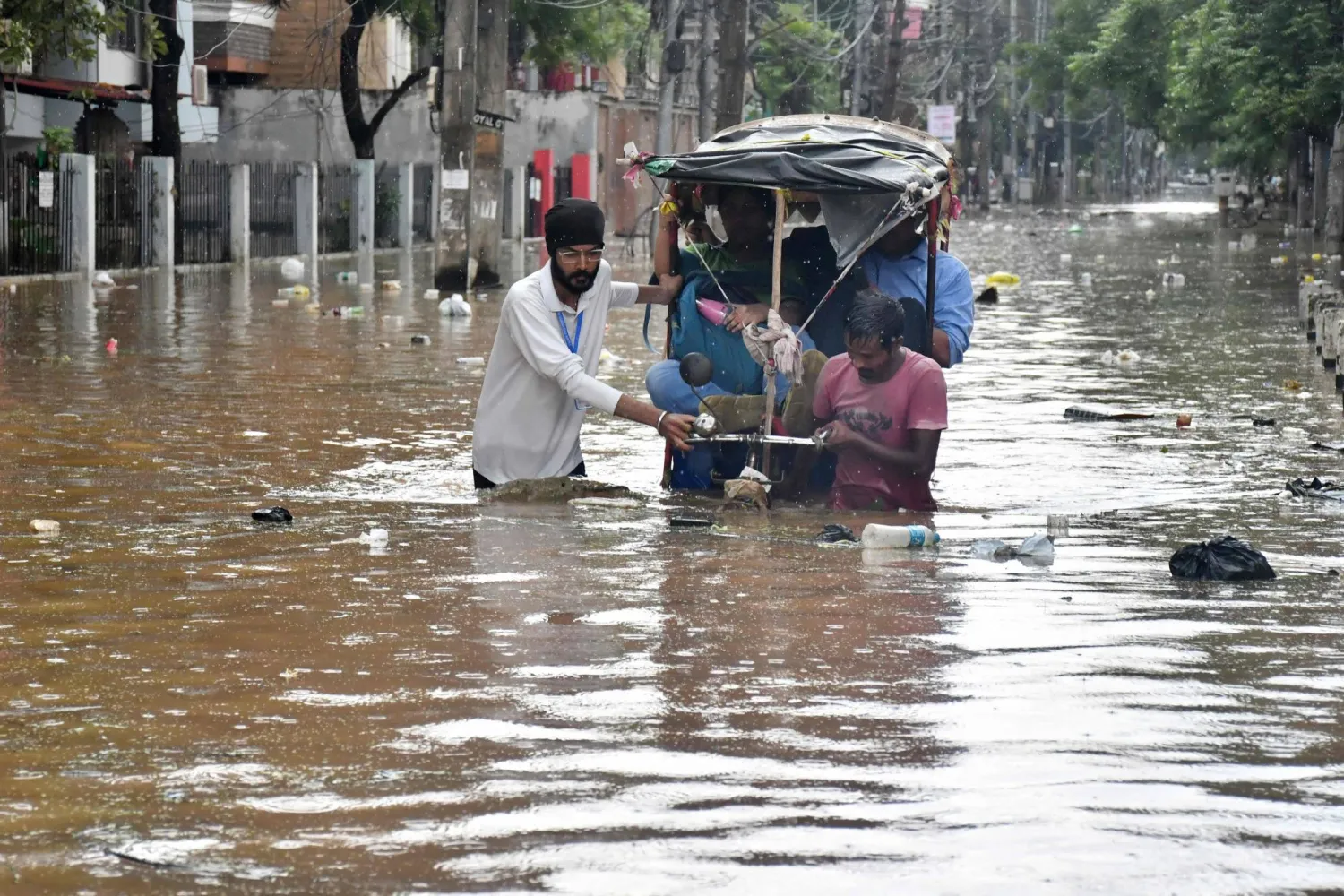 Residents wade through a flooded street following heavy monsoon rains in Guwahati on August 4, 2026. (AFP)