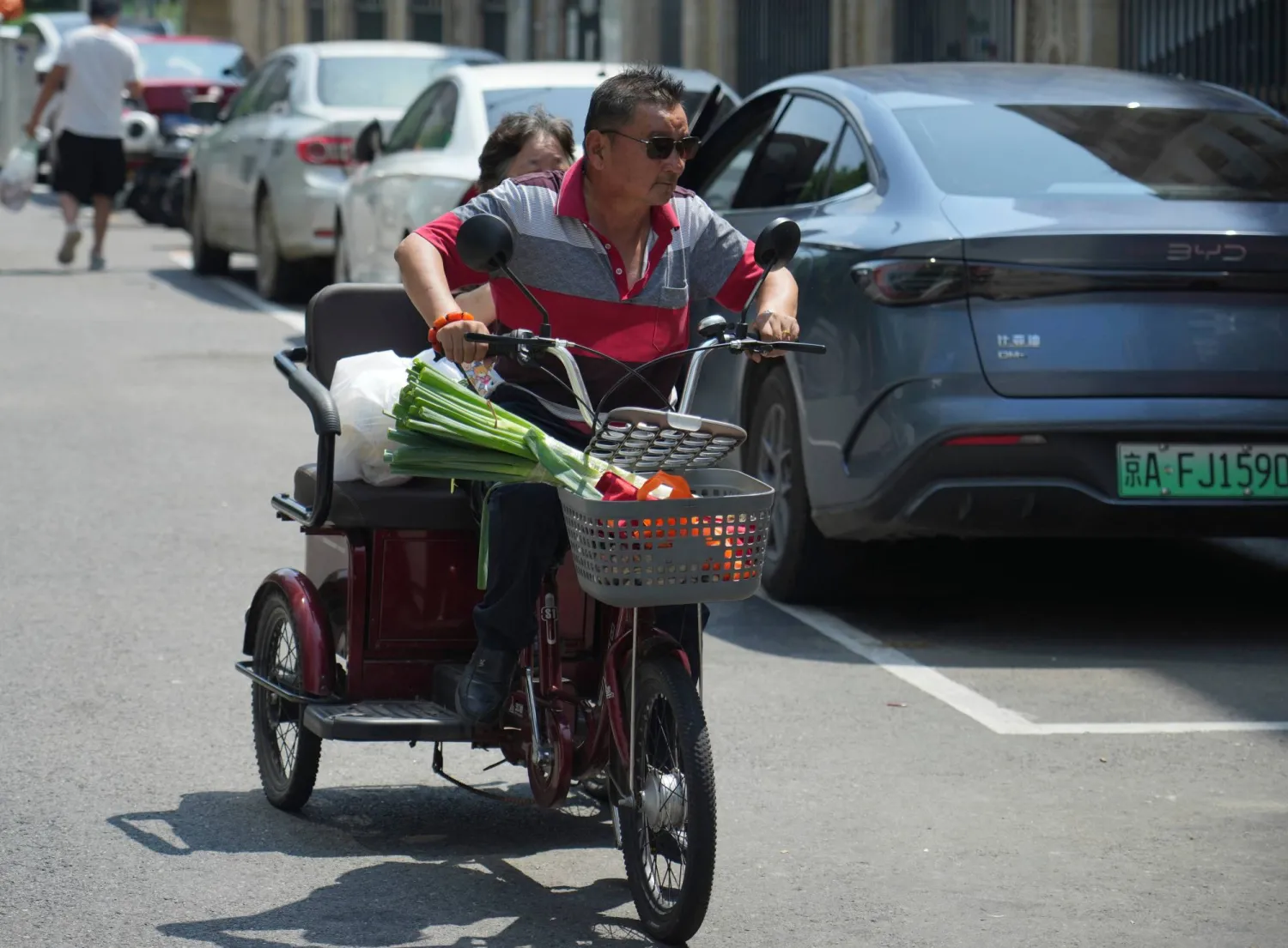 A man rides a tricycle to carry belongings in Beijing Wednesday, Aug. 5, 2026. (AP Photo/Achmad Ibrahim)