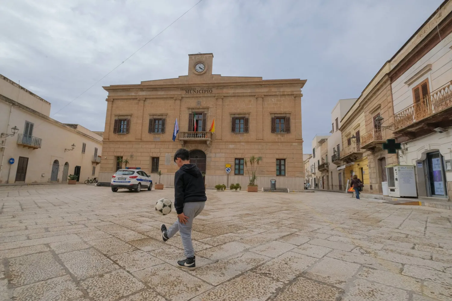 A boy plays football outside Favignana's municipal building in Favignana, Italy, May 5, 2021. (Reuters)