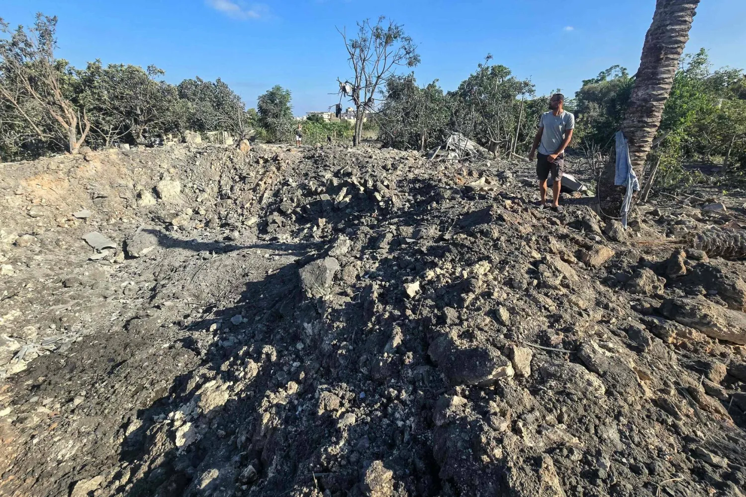 A man stands by a crater left by an overnight Israeli airstrike that targeted a house in the area of Burj al-Shamali, near Tyre, on August 6, 2026. (Photo by Kawnat HAJU / AFP) / 