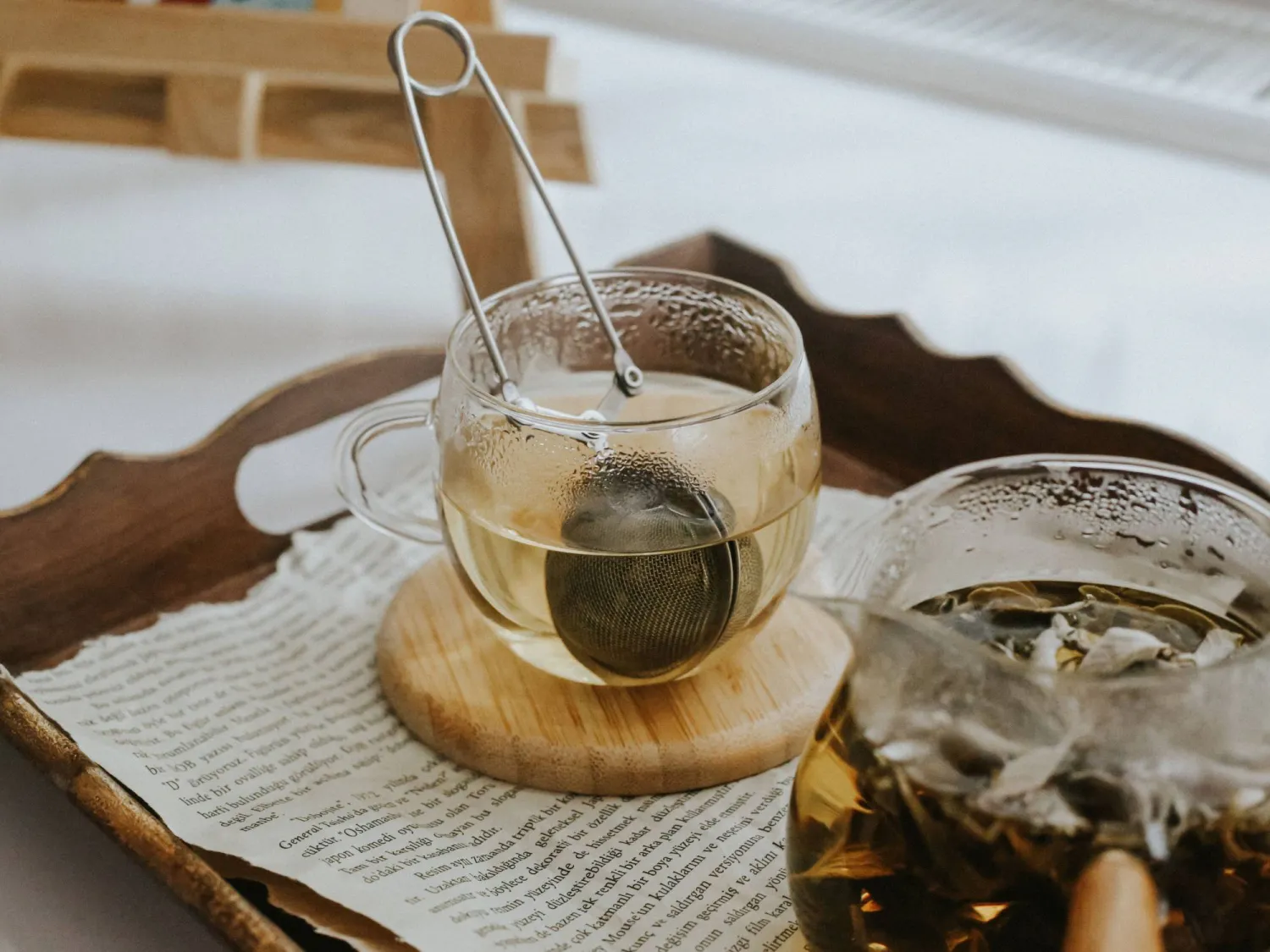 كوب شاي دافىء مع مصفاة يظهر على صينية من خشب (بيكسلز)