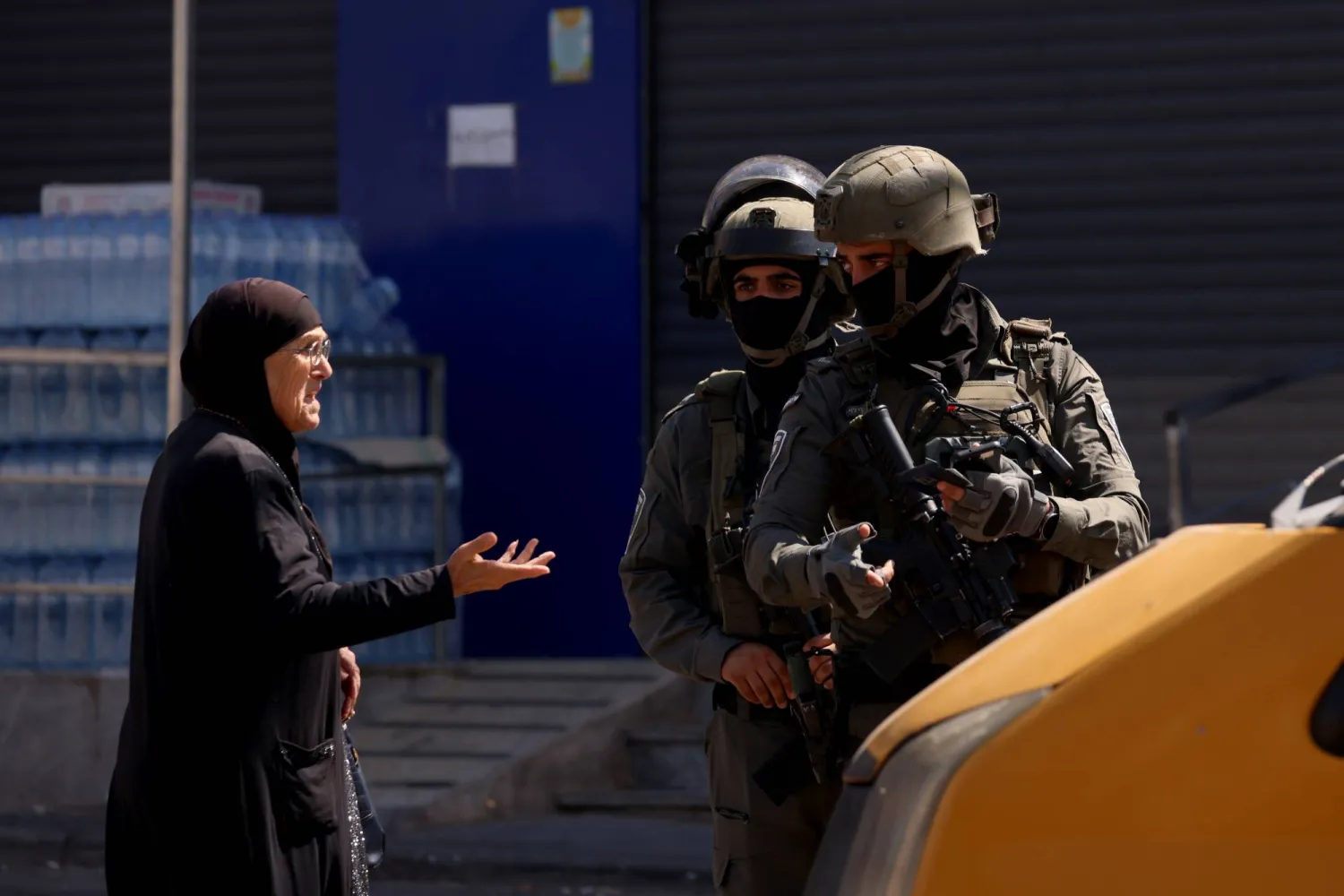 جنود إسرائيليون يوقفون مارة للتفتيش خلال عملية عسكرية بمخيم قلنديا بالضفة الغربية يوم الخميس (إ.ب.أ)