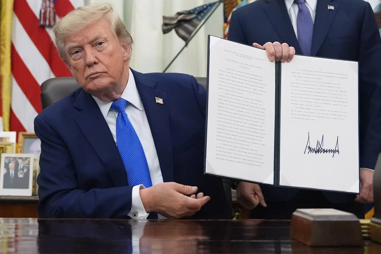 الرئيس الأميركي دونالد ترمب يرفع قراراً تنفيذياً في البيت الأبيض يوم 6 أغسطس (أ.ب)