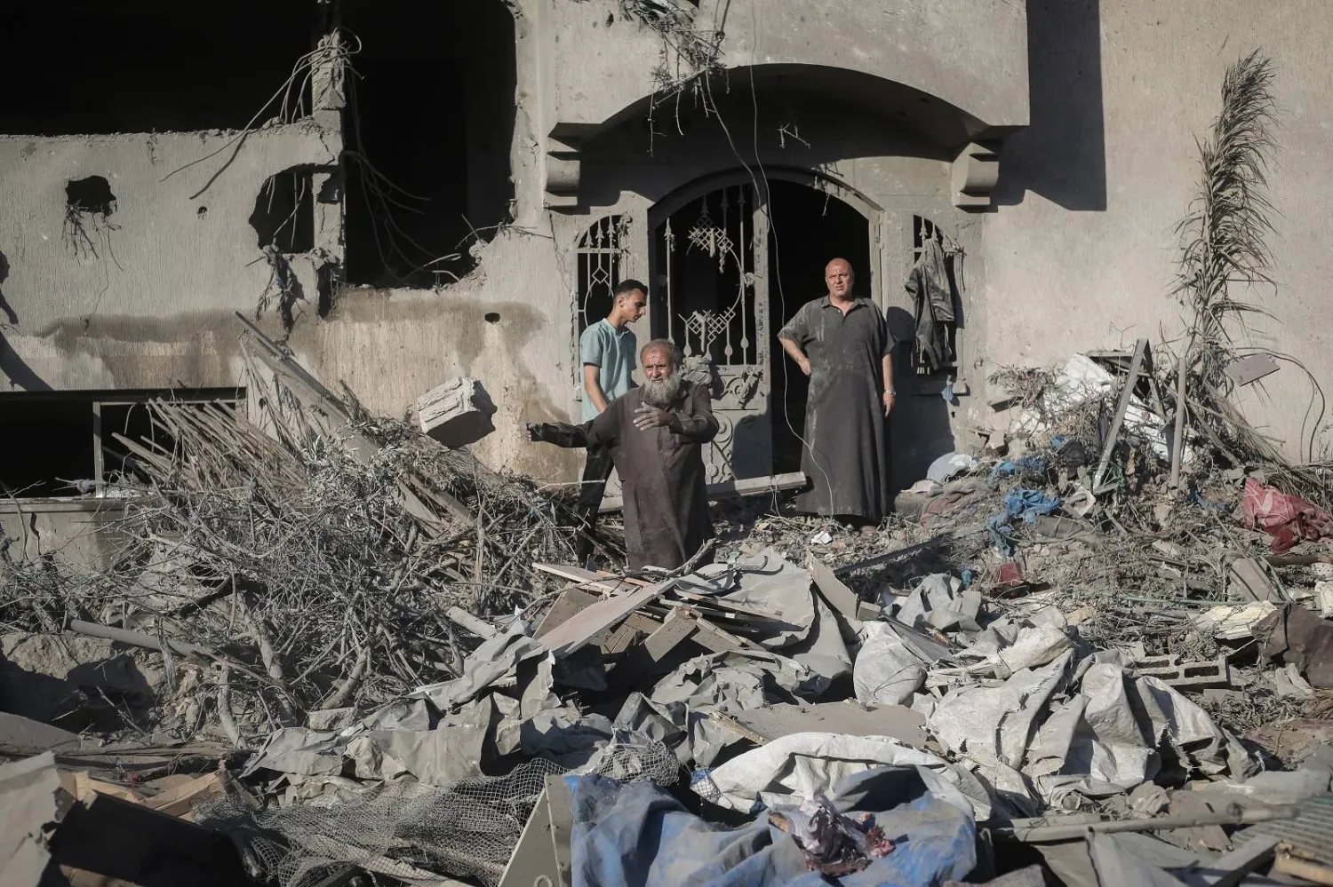 فلسطينيون يتفقدون مباني متضررة بعد استهدافها بضربات إسرائيلية في دير البلح (أ.ف.ب)