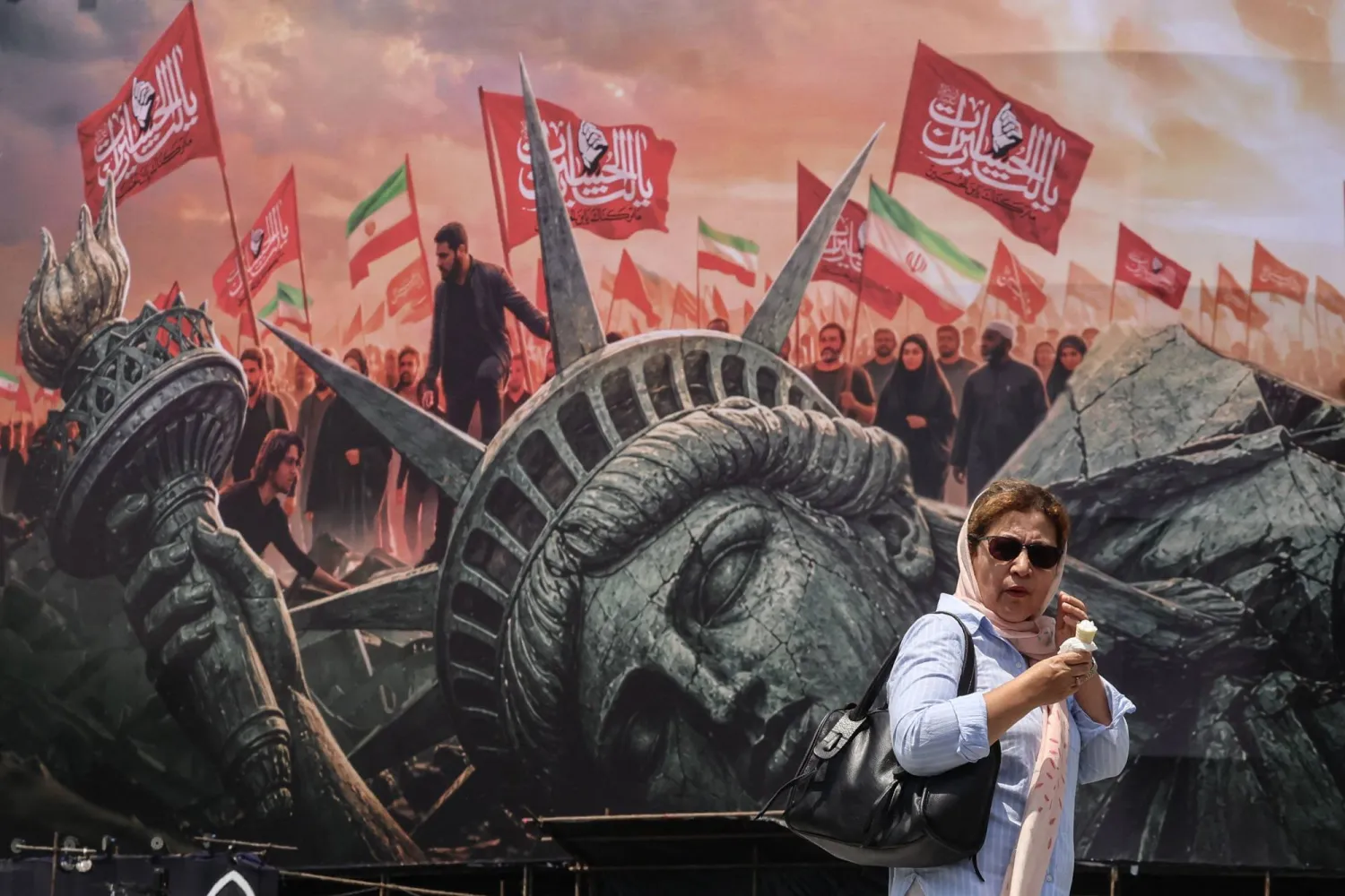 سيدة إيرانية تمر أمام لوحة ضد أميركا في طهران في 3 أغسطس (أ.ف.ب)
