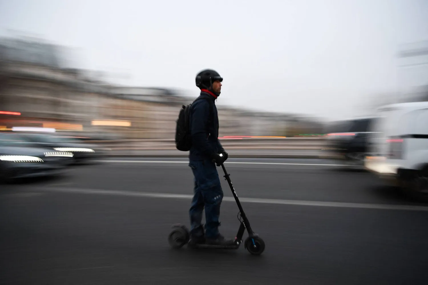 (FILES) A man rides an electric scooter past traffic on a street of Paris on December 5, 2019. (Photo by CHRISTOPHE ARCHAMBAULT / AFP)