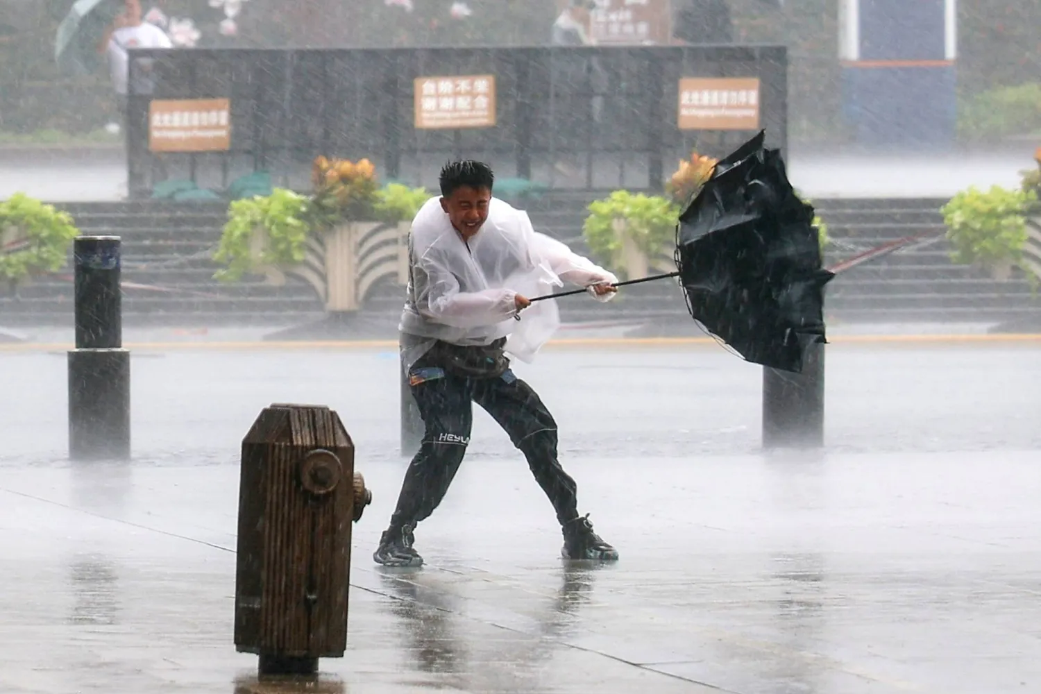  In this photo released by Xinhua News Agency, a man fights to hold onto to his umbrella in strong wind and rain ahead of Typhoon Dolphin at Huangpu District of Shanghai, China, Sunday, Aug. 9, 2026. (Wang Xiang/Xinhua via AP) 