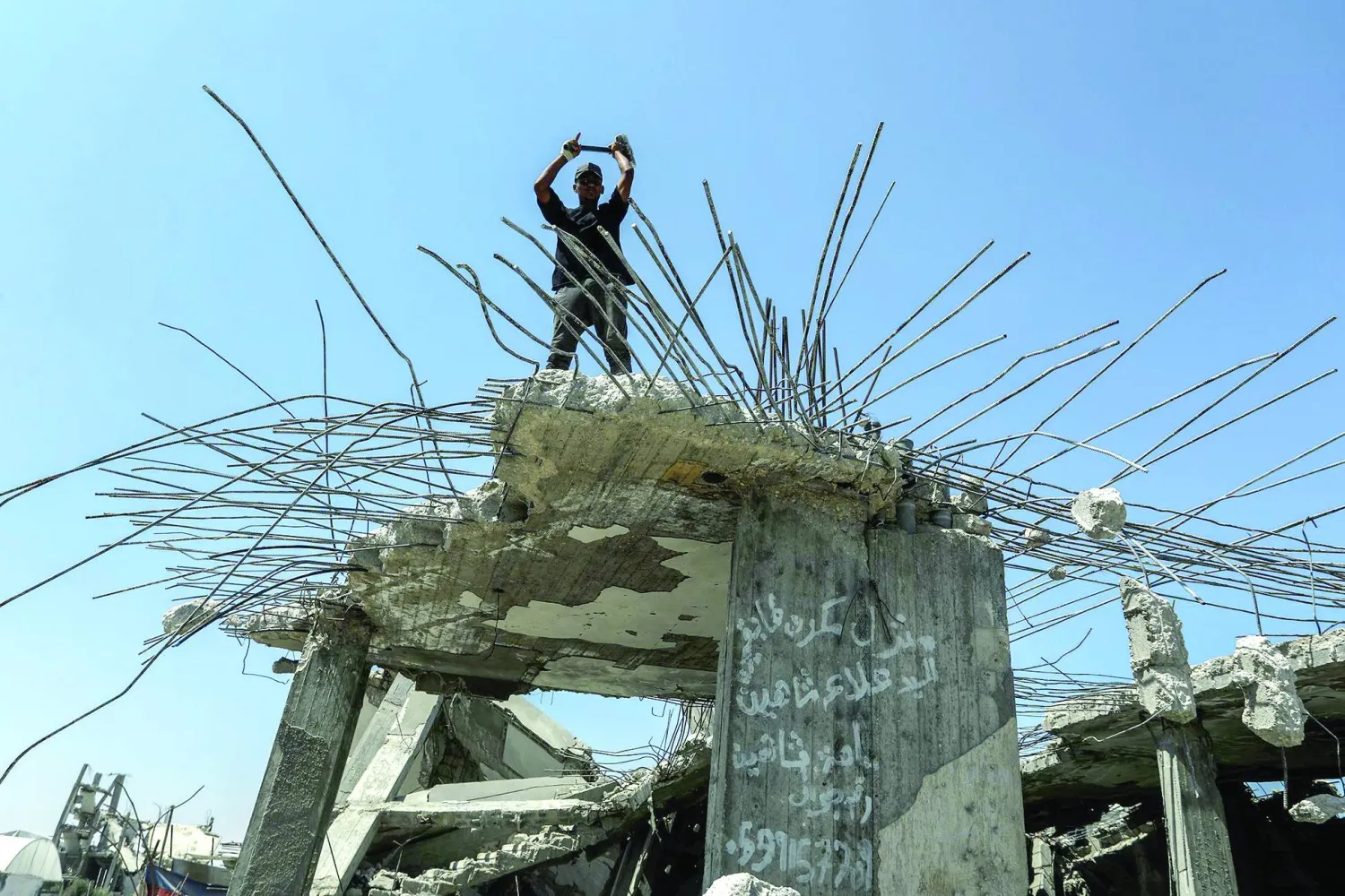فلسطيني يستخرج الحديد من أنقاض المنازل التي دمَّرها الجيش الإسرائيلي خلال الحرب في خان يونس (د.ب.أ)