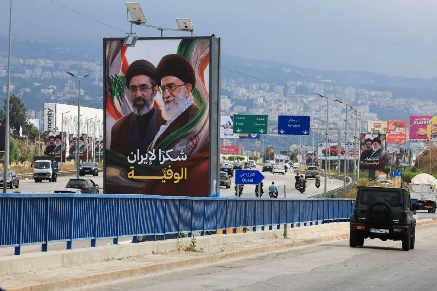 Cars and motorcycles pass billboards depicting Iran's new Supreme Leader, Mojtaba Khamenei, and his late father, Ali Khamenei, bearing the slogan "Thank you to loyal Iran," along the highway leading to Beirut's Rafik Hariri International Airport on June 22, 2026. (Reuters) 