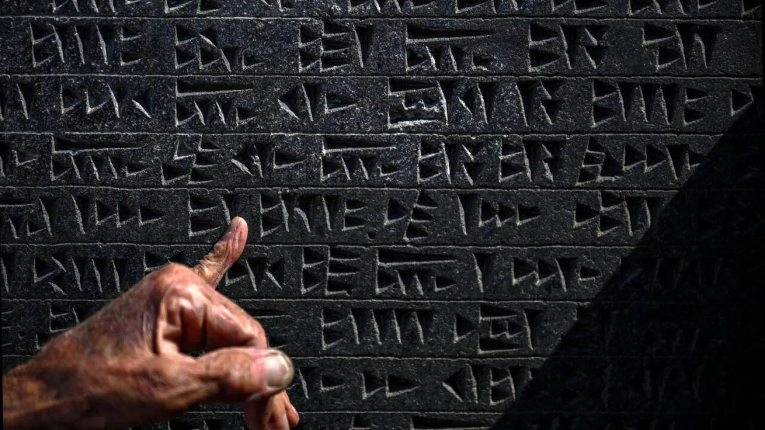 Kusman runs his finger over a tablet engraved with the ancient Urartu language. Ozan KOSE / AFP
