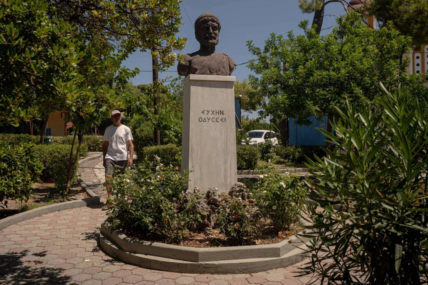 A man walks next to a bust of Odysseus in the central square of the village of Stavros, on the island of Ithaca, in the Ionian Sea, on August 3, 2026. (AFP)