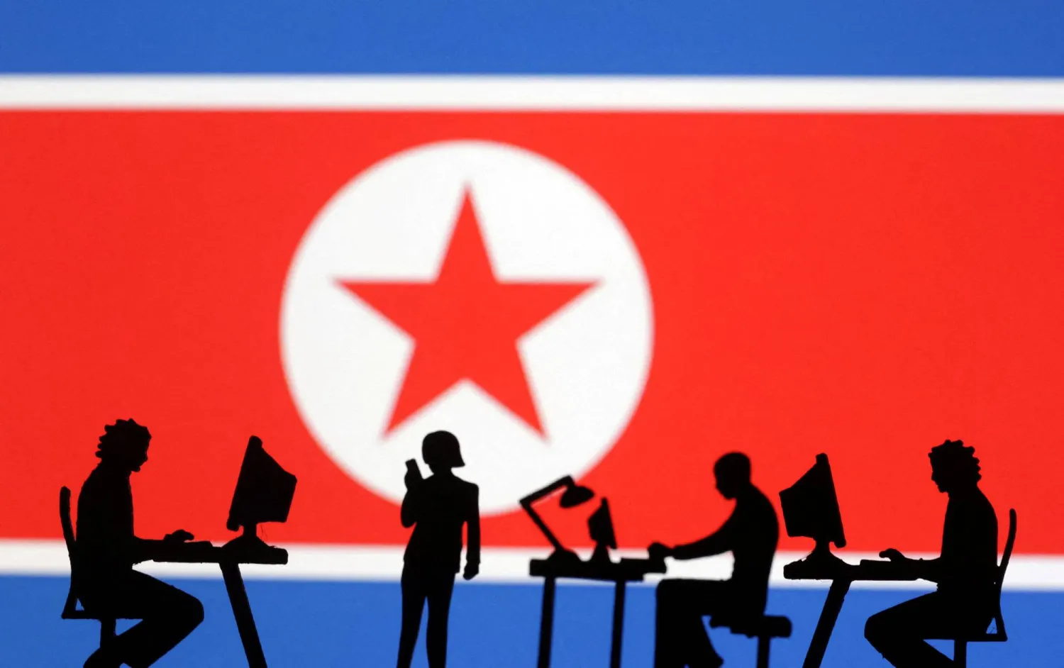 Miniatures of people with computers are seen in front of North Korea flag in this illustration taken July 19, 2023. (Reuters)