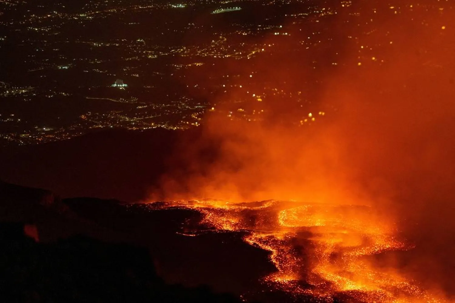 Lava flows from Mount Etna as lights from nearby communities are seen in the background during an eruption in Sicily, Italy, July 30, 2026. (Reuters)