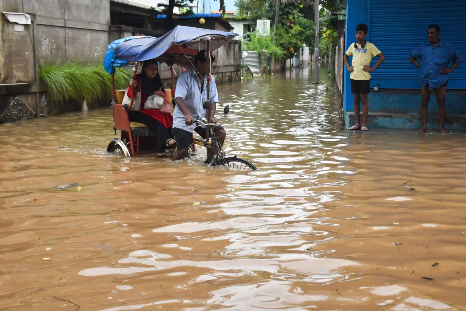 A resident commutes in a cycle rickshaw through a flooded street following heavy rainfall in Guwahati on August 9, 2026. (Photo by Biju BORO / AFP)